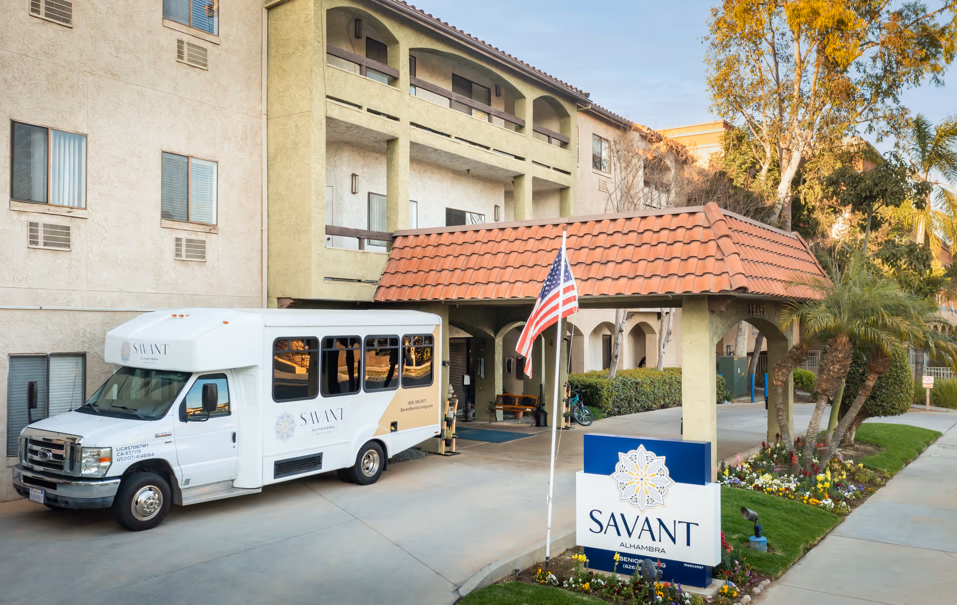 A white Savant bus parked at the Alhambra Senior Villa entrance under a tiled canopy.