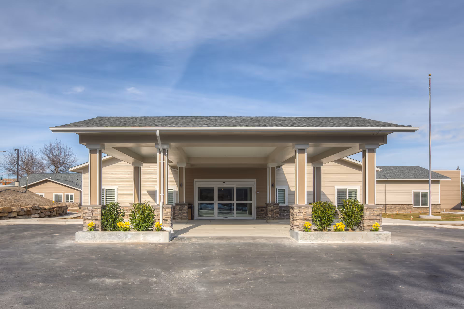 Front view of a modern senior care center entrance with covered porte-cochere and landscaping.