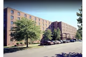 Exterior brick building of Lutherwood senior facility with trees and parked cars.