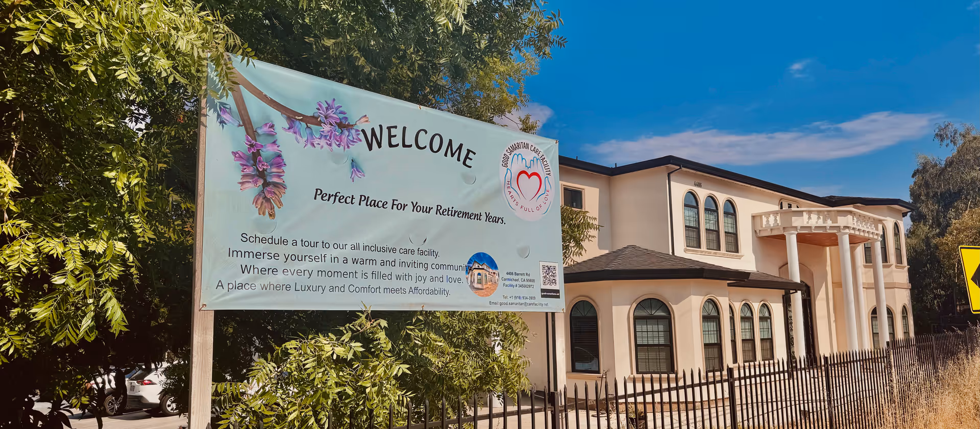 Beige senior living facility exterior with a large Welcome banner and trees.
