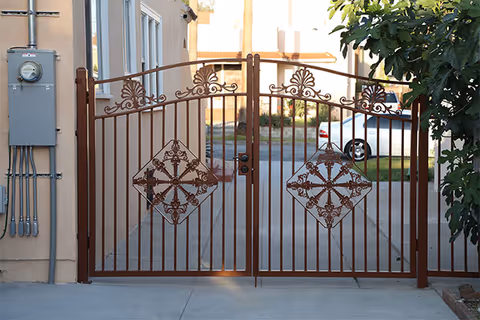 Decorative wrought-iron gate blocks the driveway at a Grant Serenity Homes entrance.