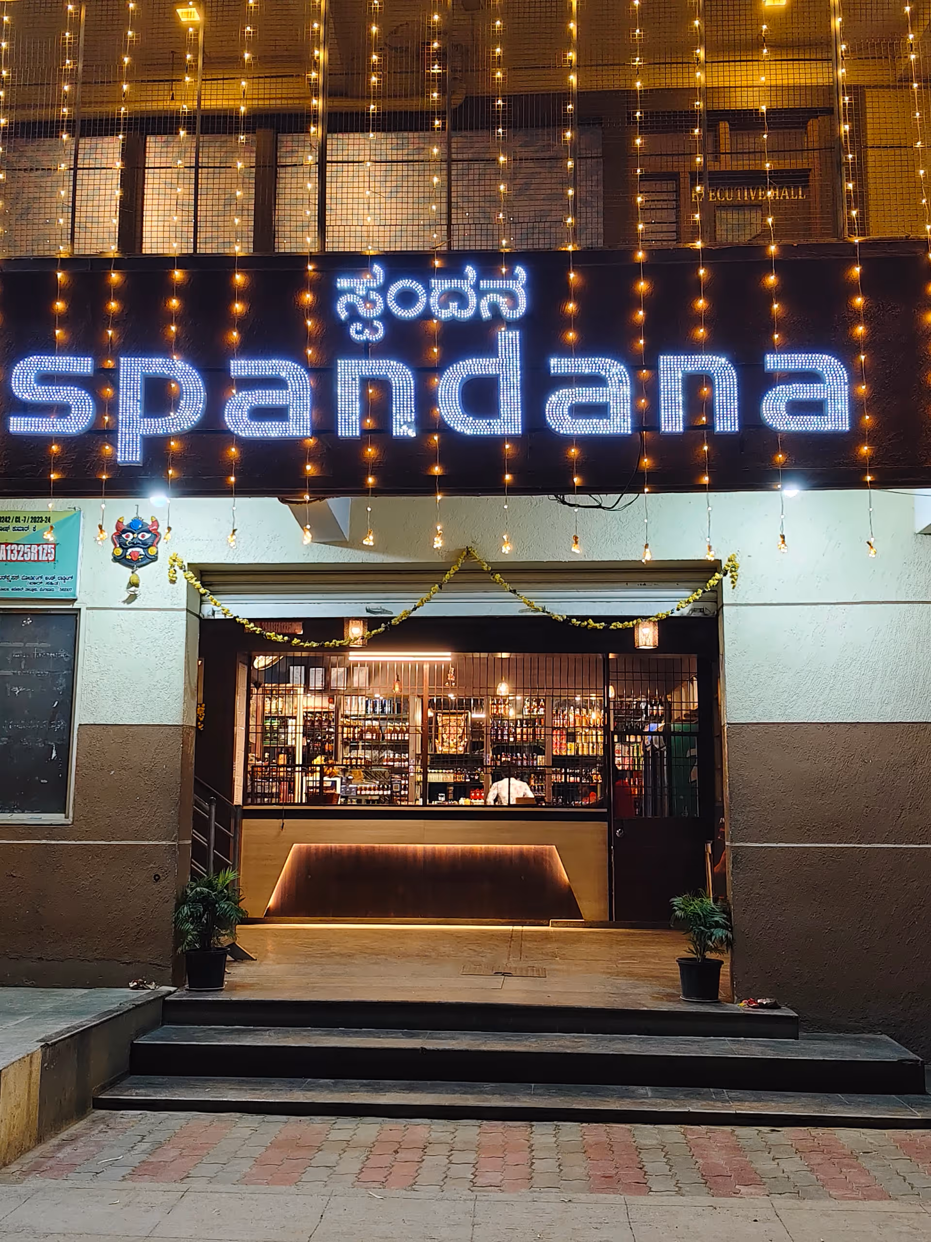 Storefront entrance with a bright blue Spandana sign and string lights.