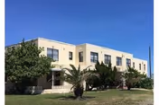 Beige two-story senior living facility front with palm trees and manicured lawn