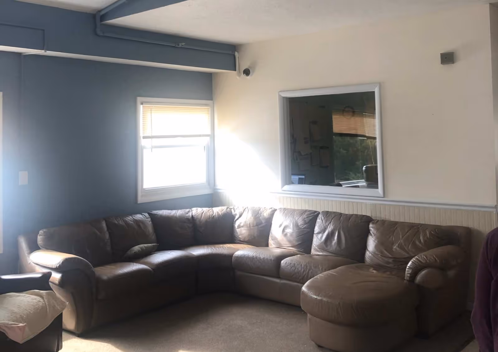 Large brown leather sectional sofa fills a blue-walled living room.