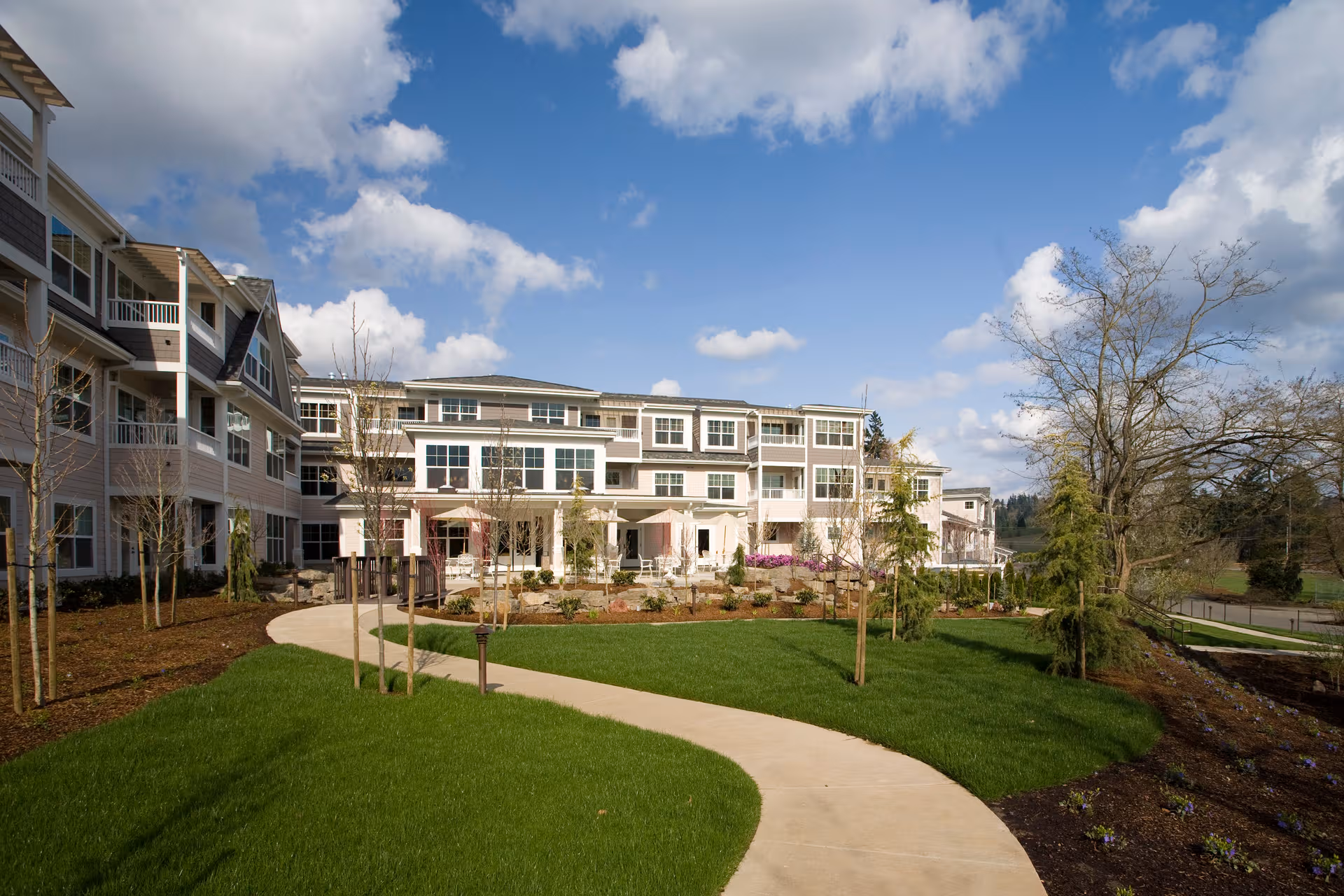 Exterior view of The Stafford Retirement Community with a curved walkway and green lawn