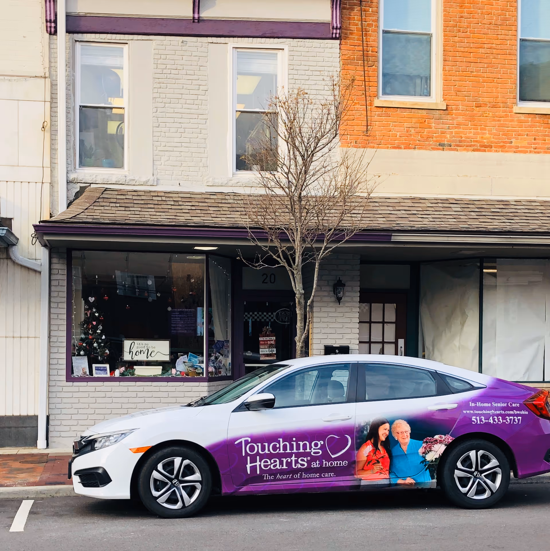 Exterior storefront with a wrapped car advertising Touching Hearts at Home.