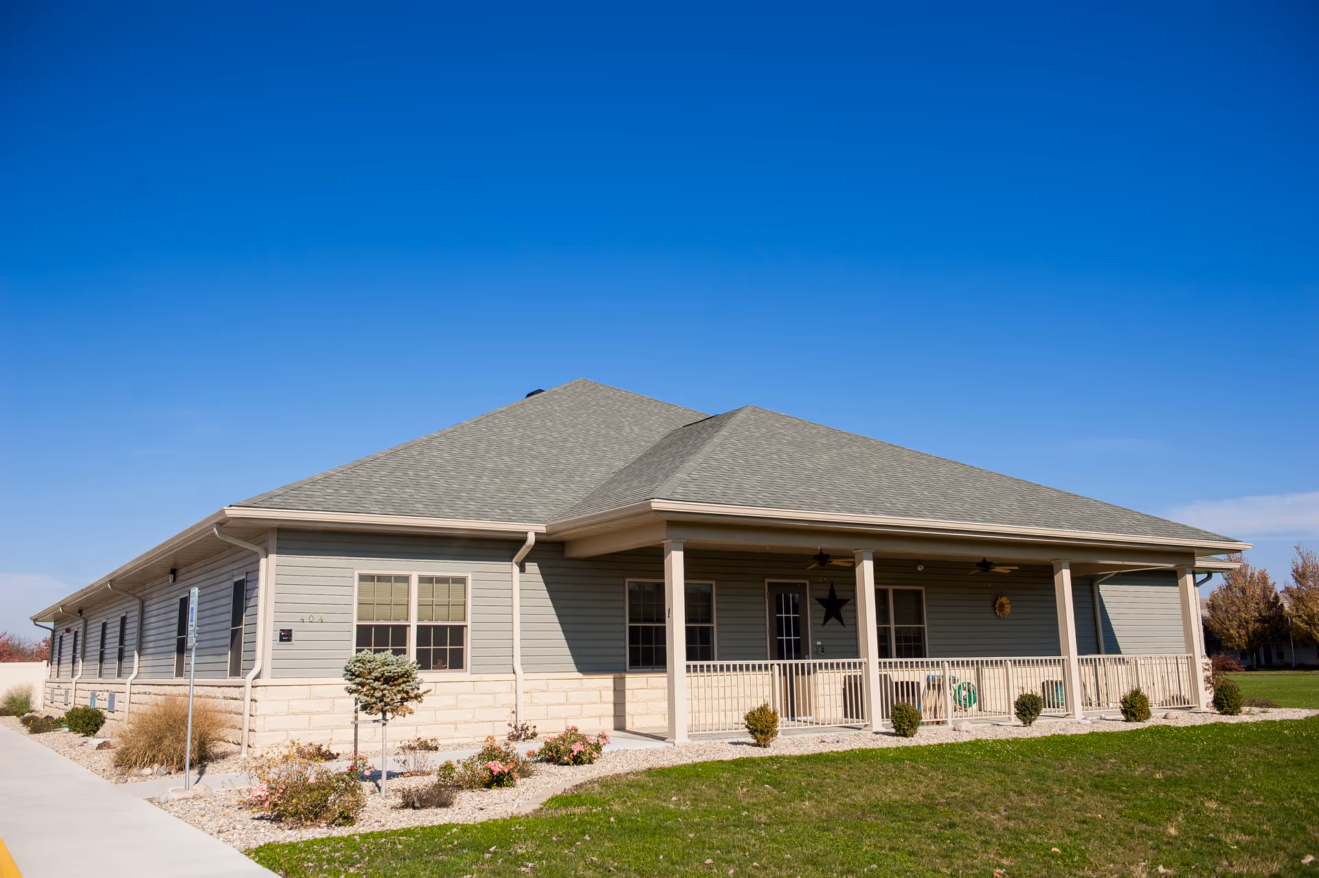 Single-story facility with a wide front porch, columns, railing, and manicured landscaping.