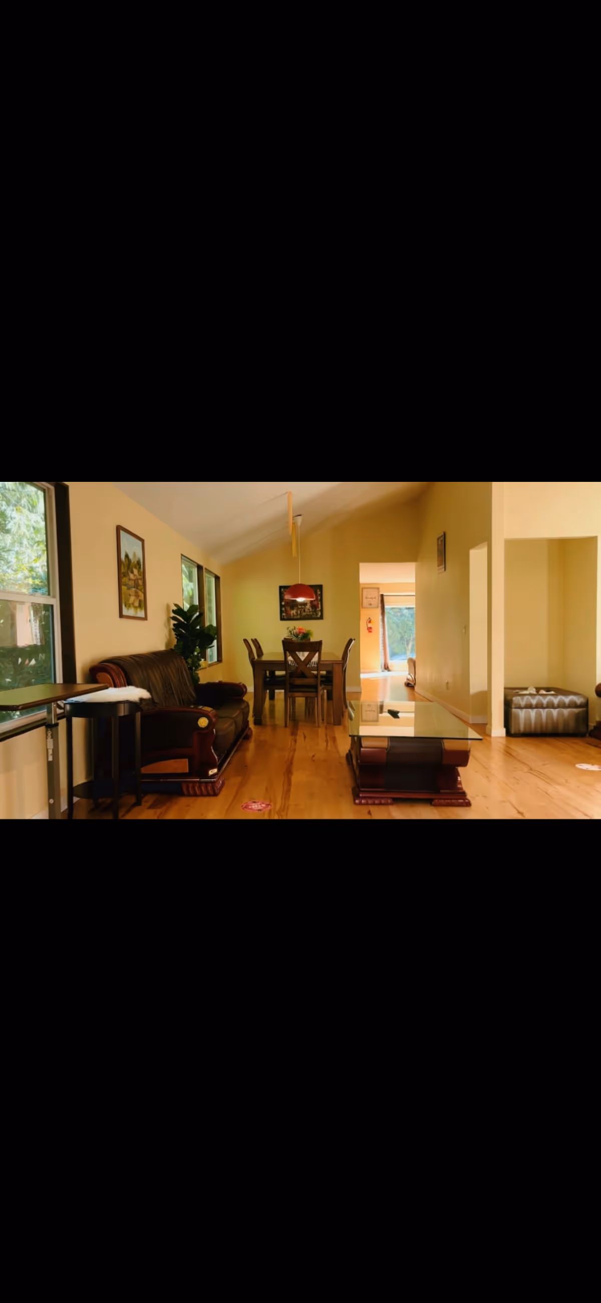 Joyful Care Home living room with sofa, coffee table, dining area, and windows.