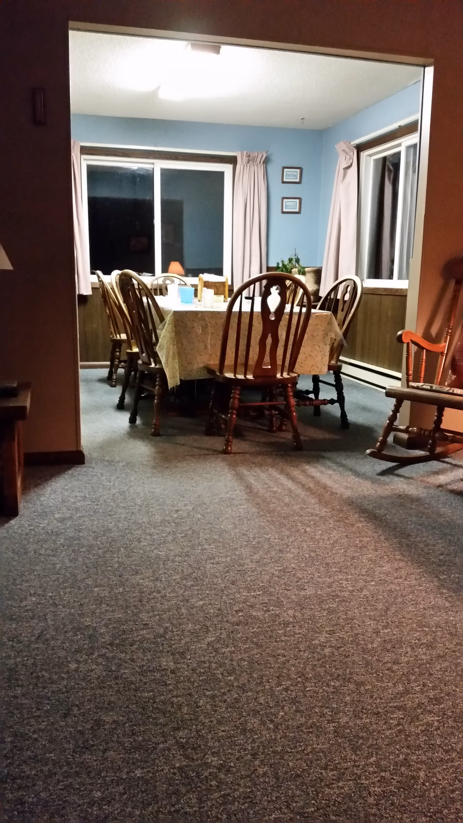 A dining room with a long table and wooden chairs, blue walls in a residence.