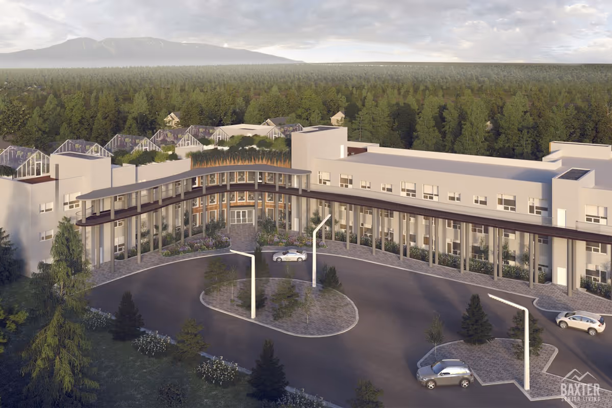 A modern curved-front senior living building with circular driveway, landscaping, and surrounding pine forest.