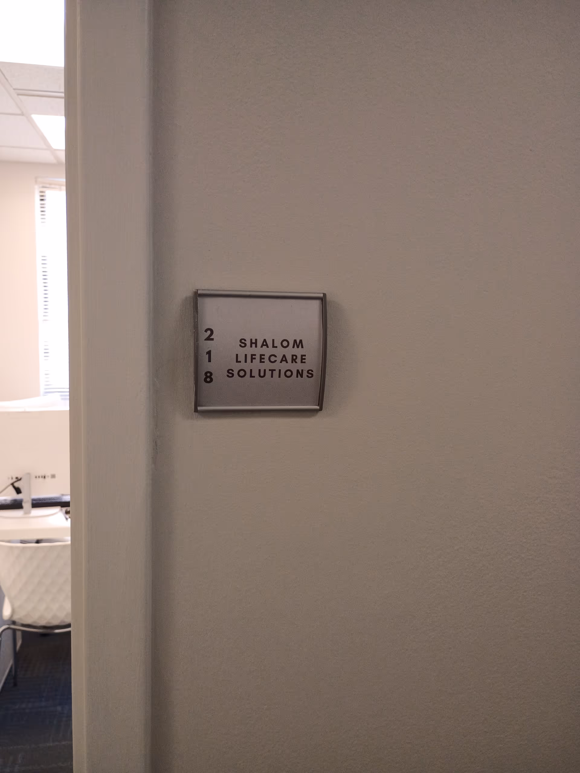 Wall plaque reading Shalom Lifecare Solutions mounted on a hallway wall.