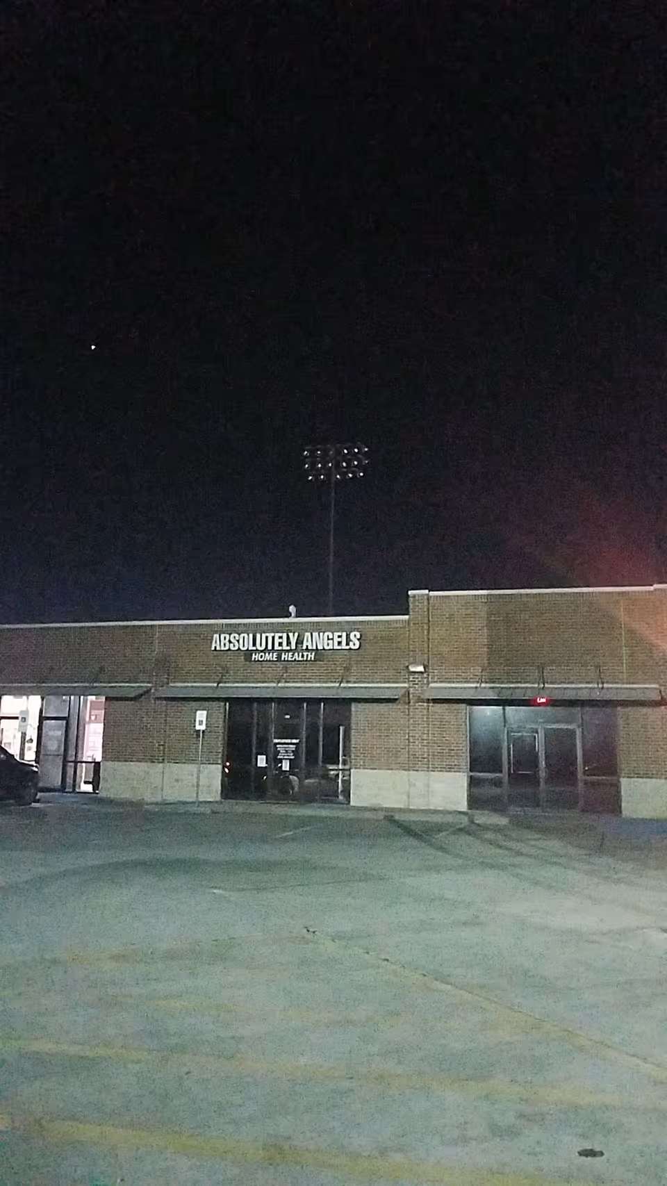 Night exterior of a brick building with ABSOLUTELY ANGELS sign and entrance.