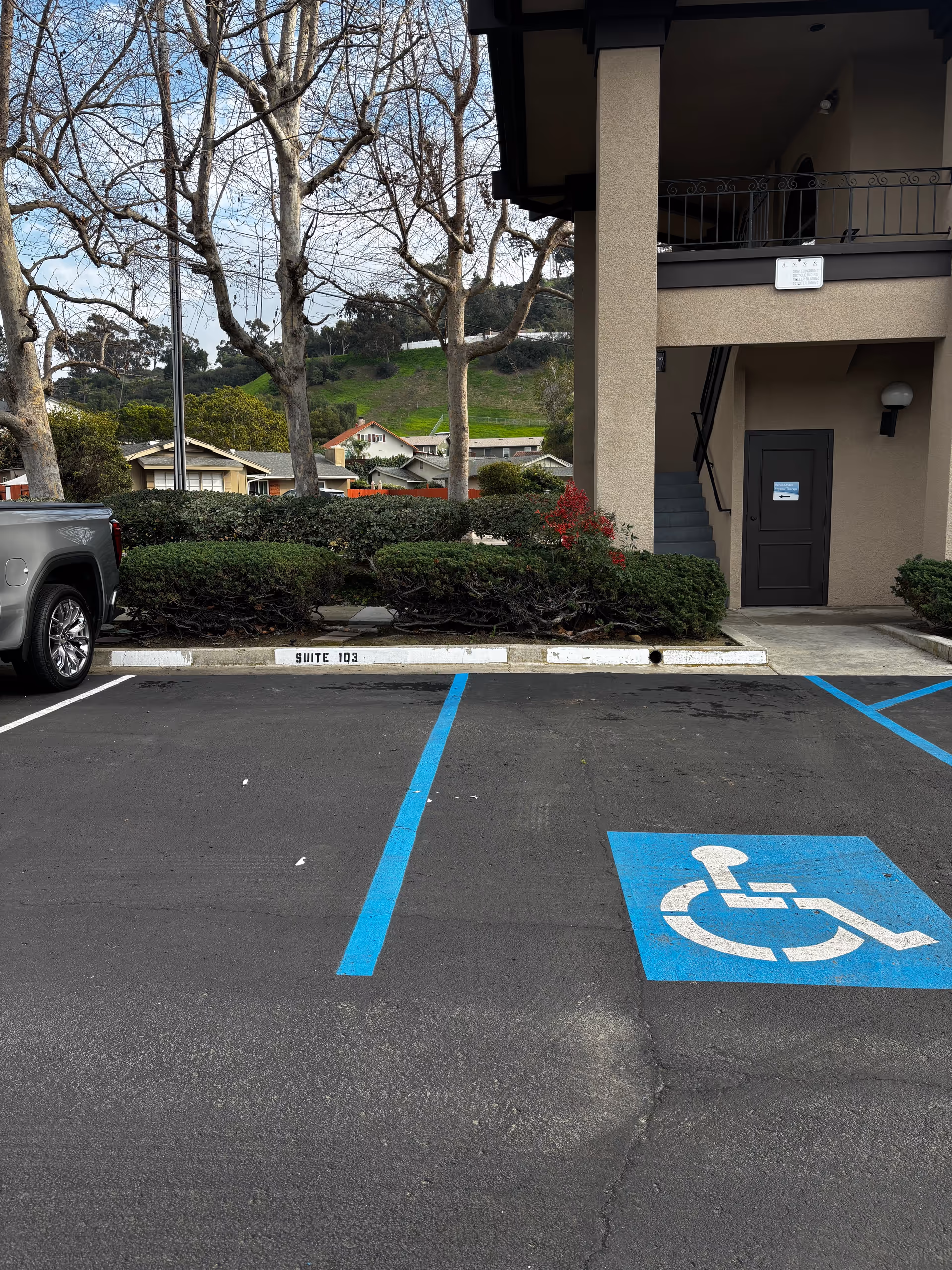 Exterior of a senior living building with parking, a handicap space, and stairs.