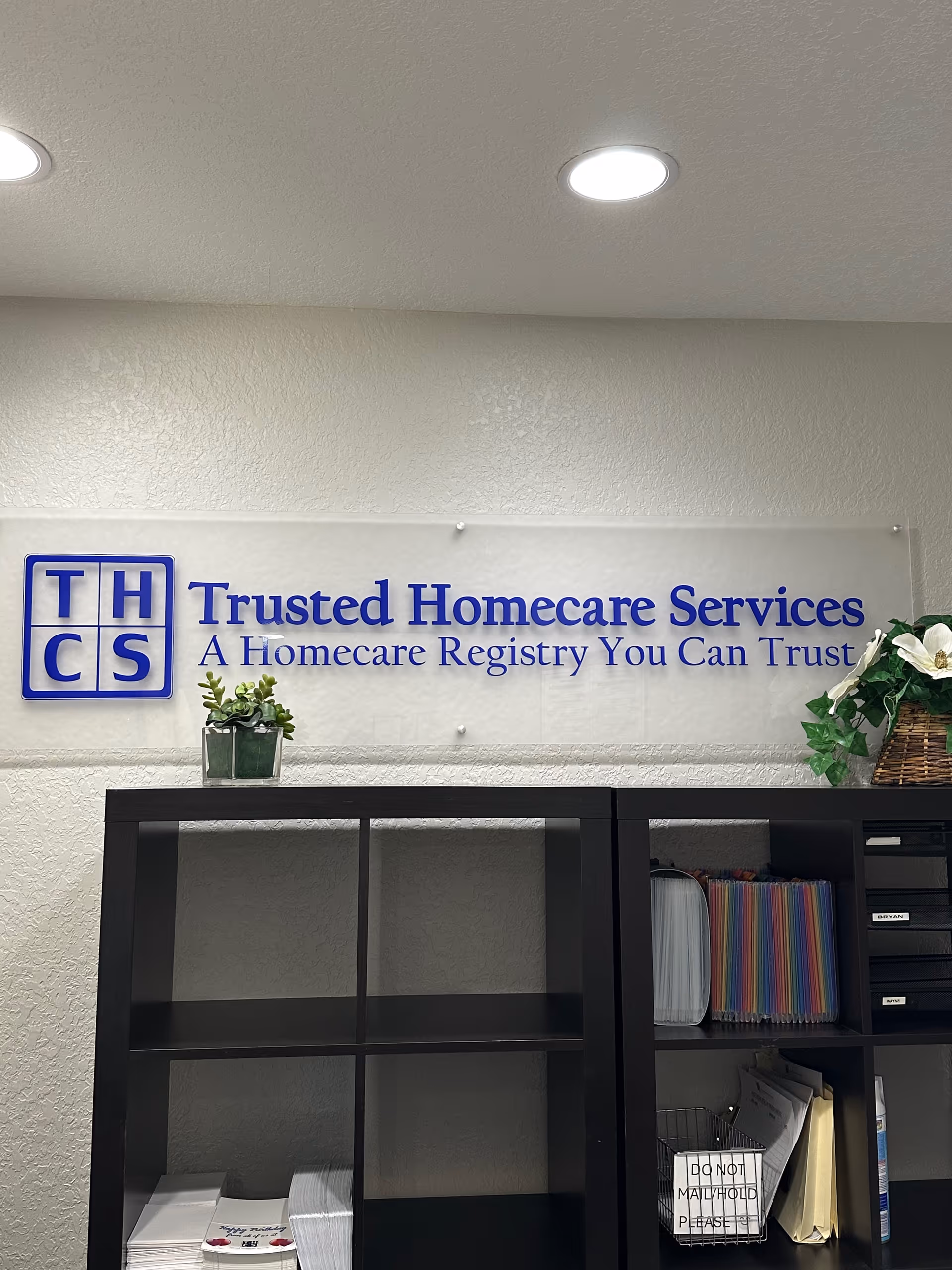 Indoor reception area with a Trusted Homecare Services sign and shelving unit.