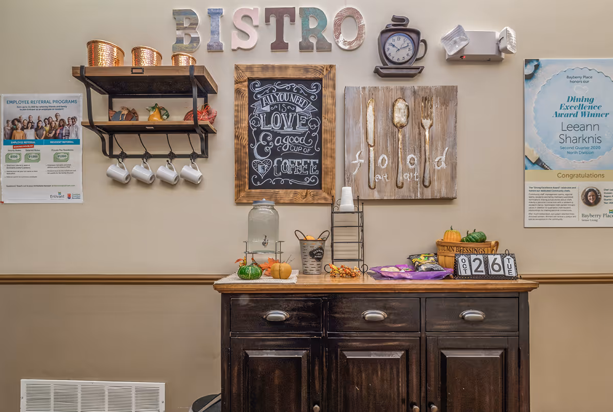 Bistro-style service area with mugs, chalkboard, pumpkins on a dark wood cabinet.