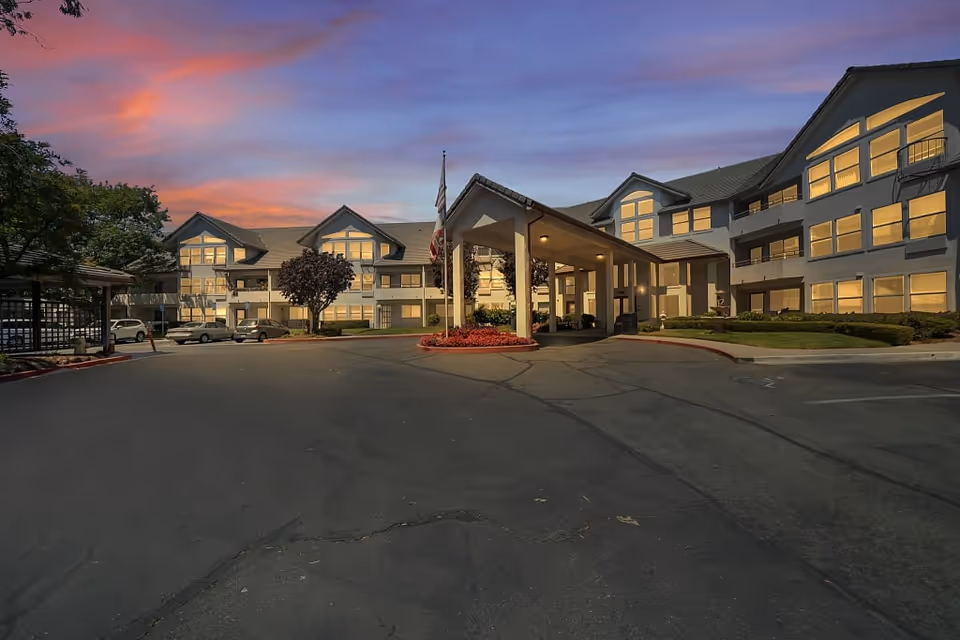 Sundown exterior view of Truewood by Merrill, Pinole, showing the front entrance and parked cars.