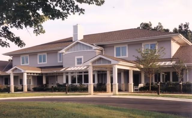 Exterior view of a two-story senior living facility with a covered entrance and landscaping.