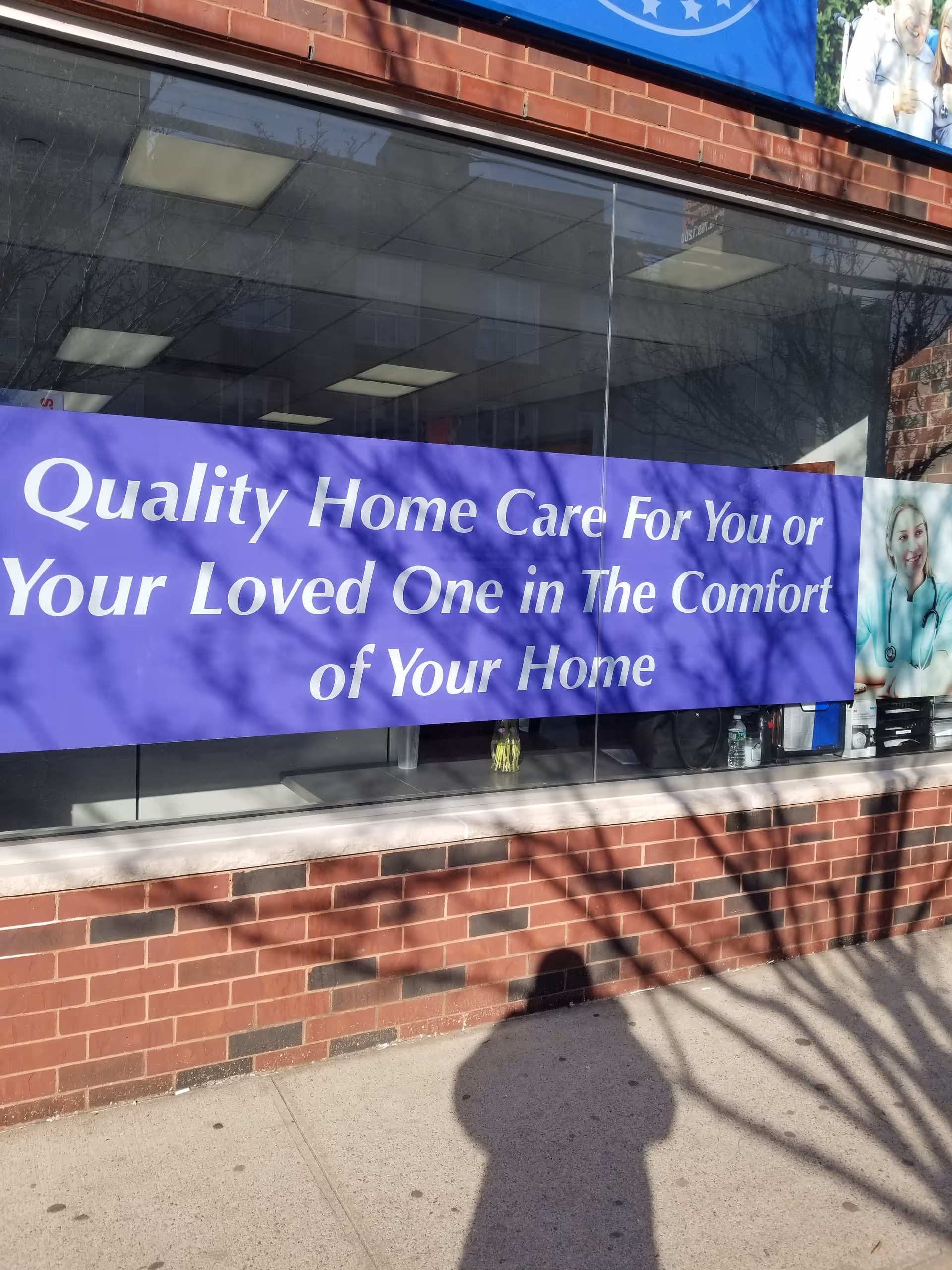 Brick storefront with a large purple banner advertising home care in the window.