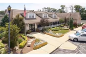 Exterior view of Morristown Manor senior living facility with entrance, landscaping, flag, and parked cars.