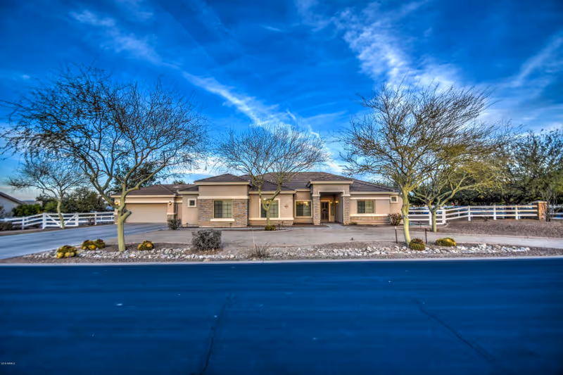 Single-story assisted living facility with a brick front, bare trees, and a white fence.