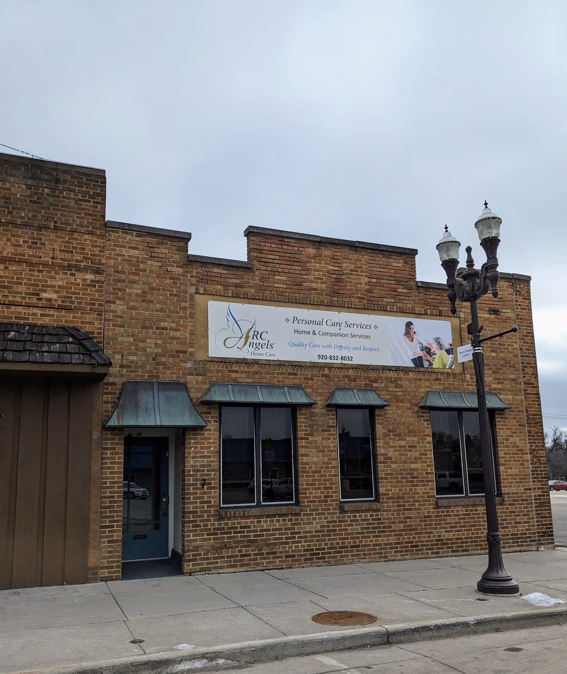 Brick building exterior with ARC Angels Home Care sign and storefront windows.