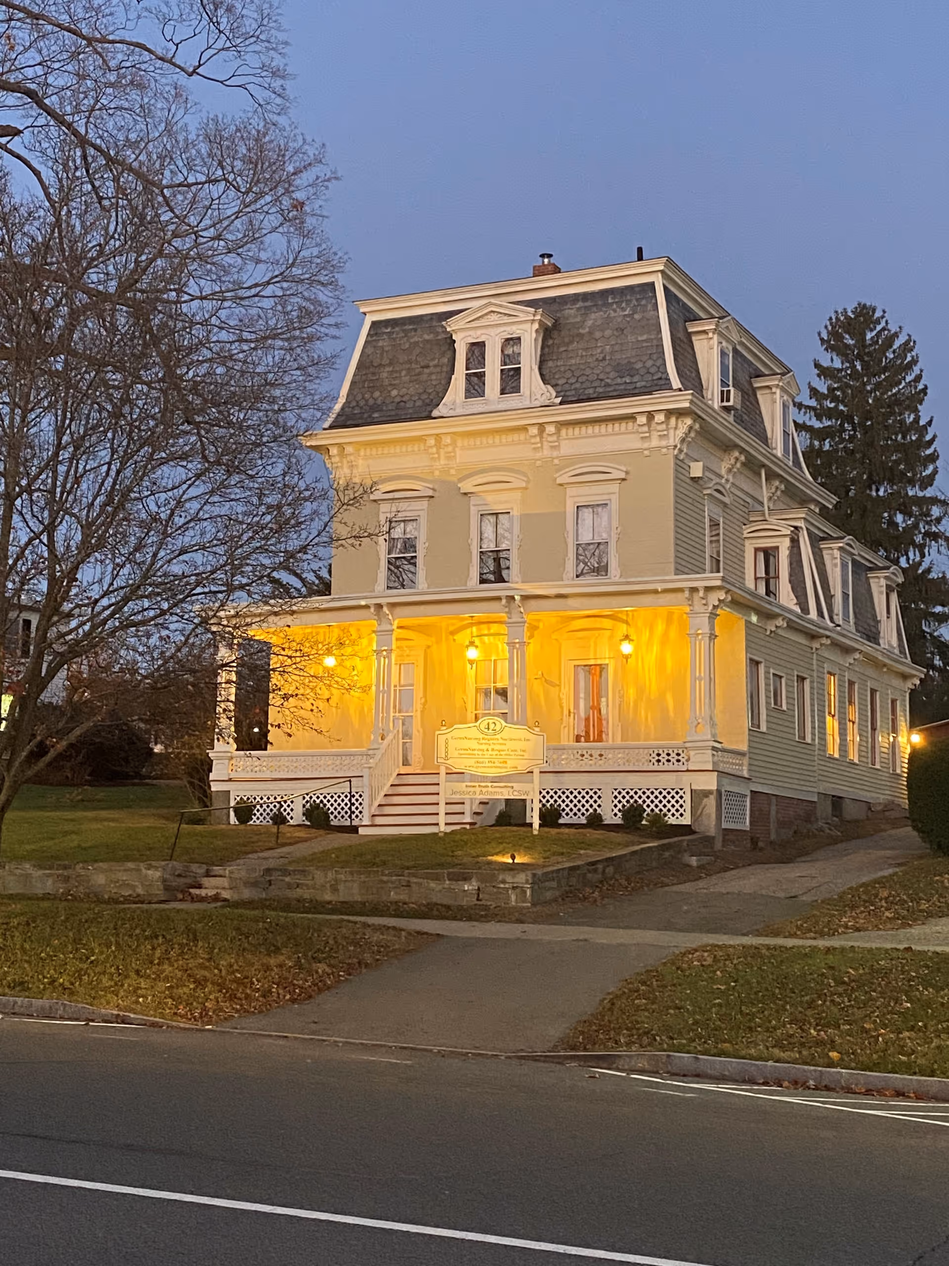 Victorian-style care home with warm porch lights and a sign at the front entrance.