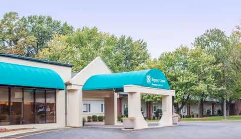 Exterior view of Regency Center facility with turquoise canopies at entrance and surrounding trees.