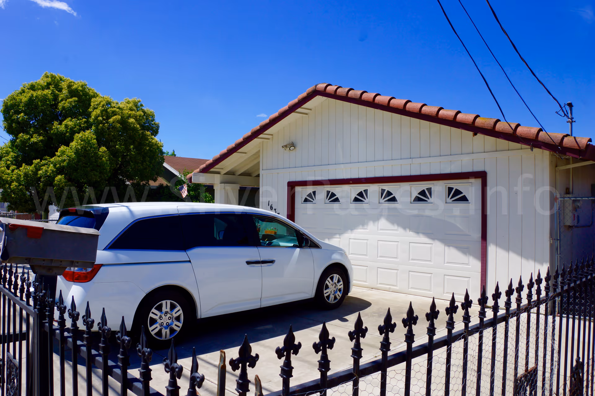 Exterior view of Arlyn's Guest Home: white garage with red trim and a parked minivan