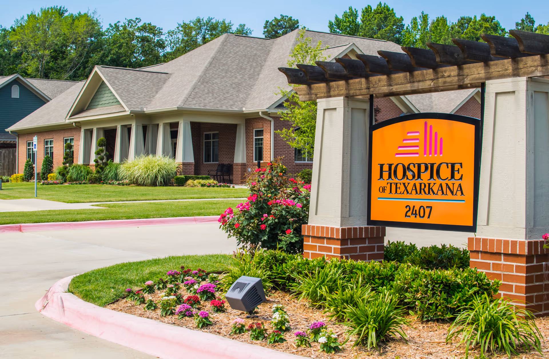 Exterior view of Hospice of Texarkana facility with orange sign and landscaped entrance