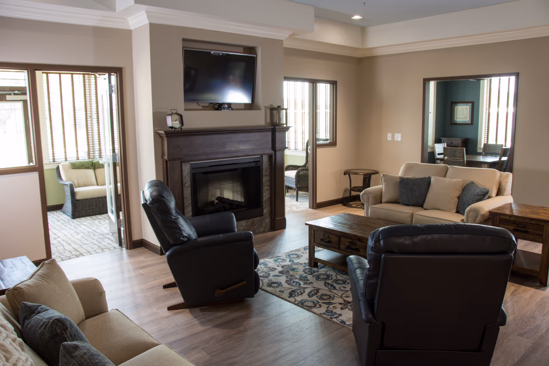 Cozy living room in a senior facility with fireplace, sofas, and a TV.