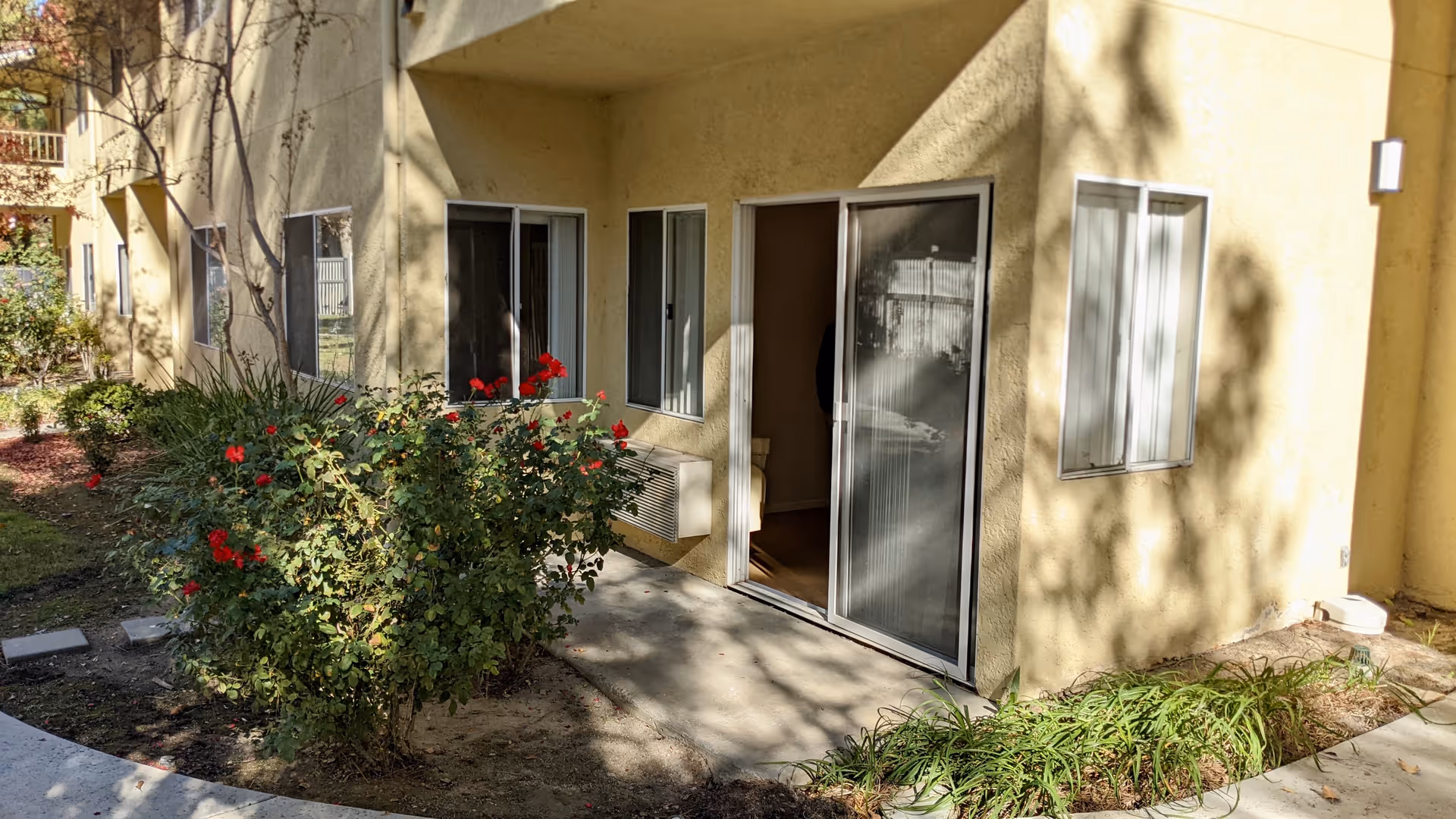 Exterior view of Sunrise at Sterling Canyon unit with sliding doors, shrubs, and patio.