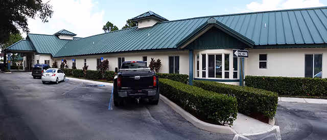 Exterior view of Hidden Pines Assisted Living with parked cars and manicured hedges.