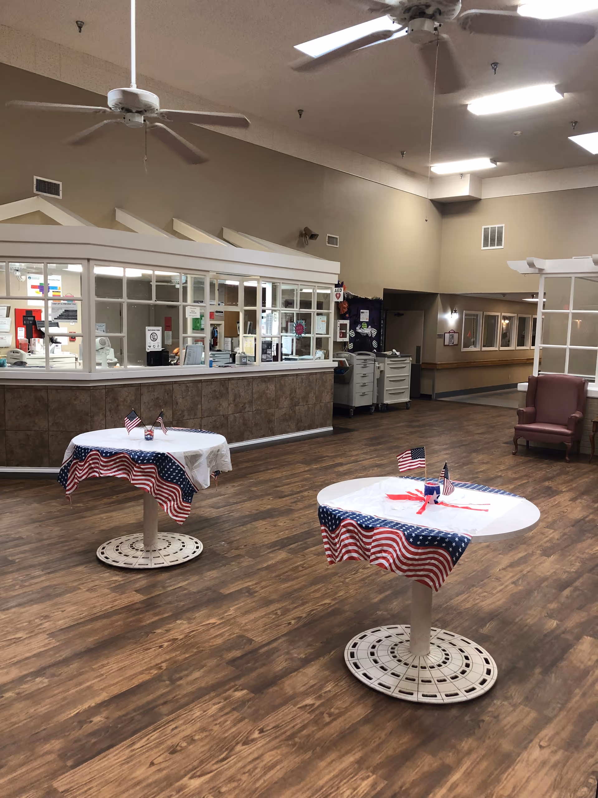 Two round tables with patriotic tablecloths and small flags in a spacious indoor lounge area.