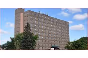Tall brick Faith Haven Inc senior living building with many windows and trees.