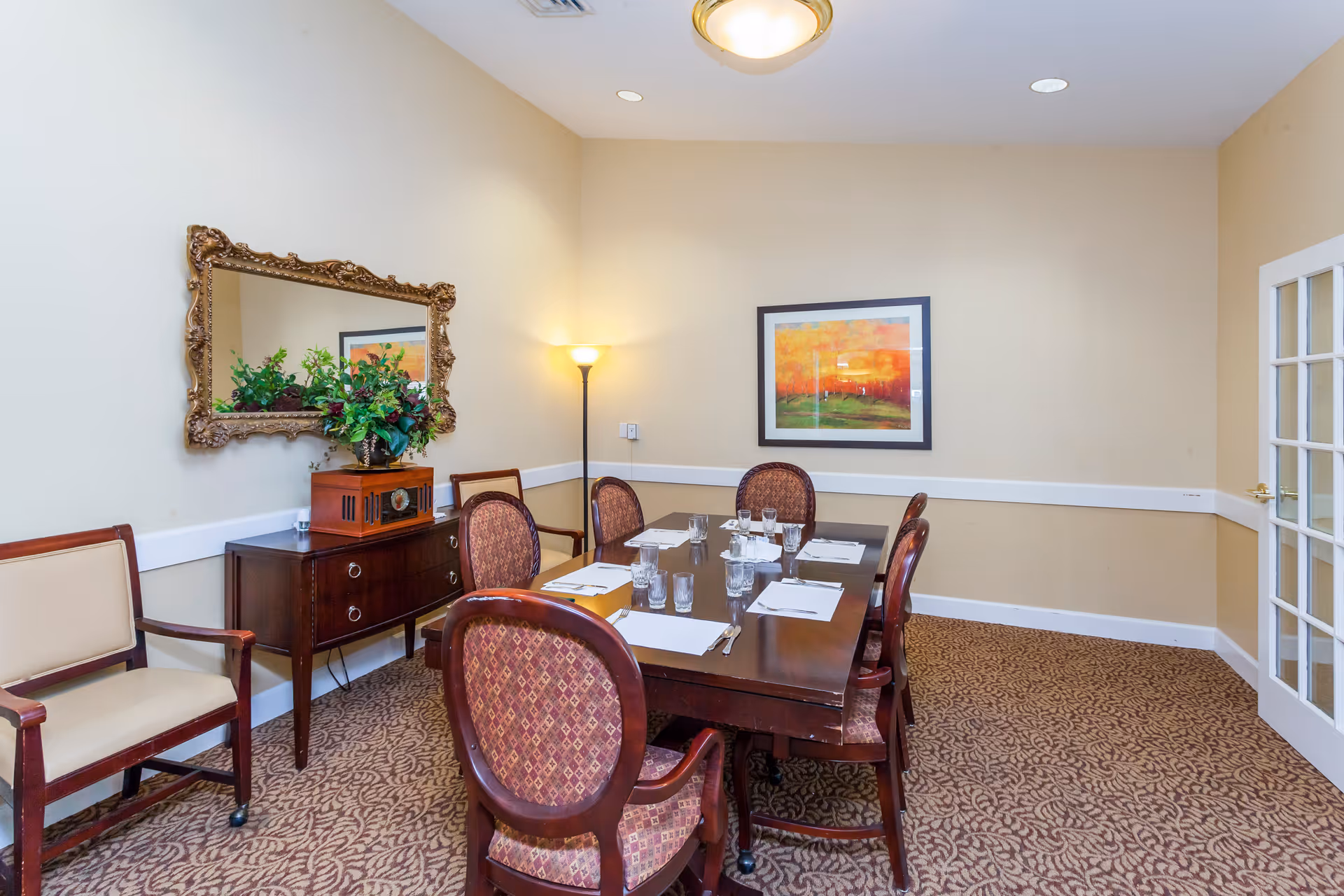 A formal dining room with a long wooden table, chairs, and place settings.