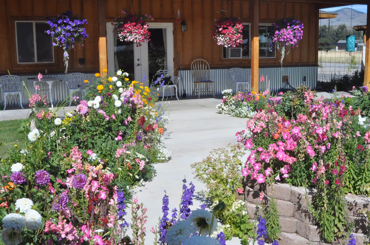 Front porch of Jamie's Place Adult Family Home with colorful flower beds and hanging baskets.
