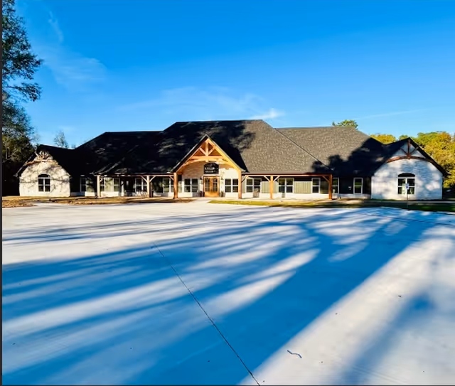 Front view of McKee Assisted Living and Memory Care facility with wide driveway and blue sky.