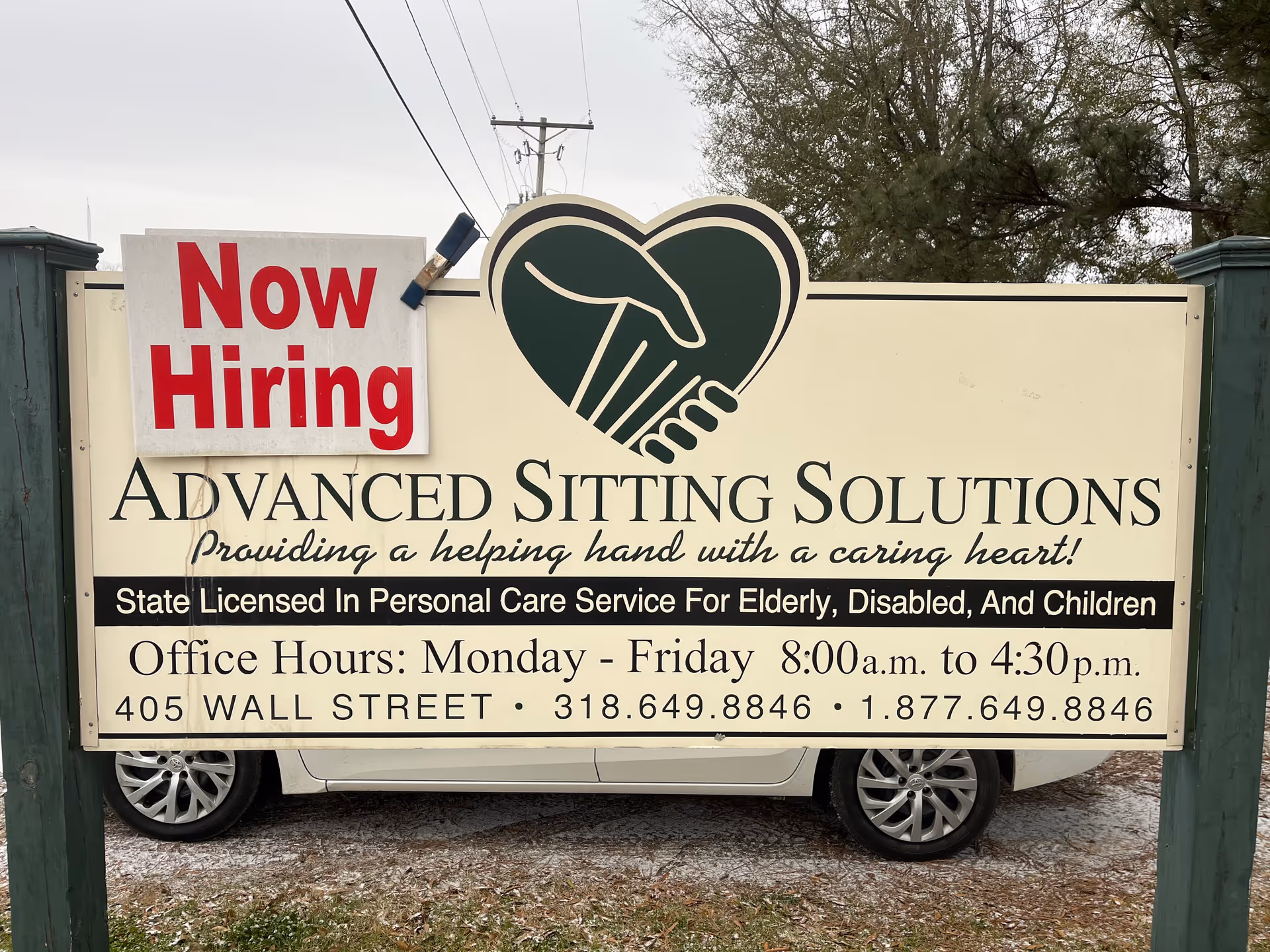 Front sign outside Advanced Sitting Solutions featuring a Now Hiring poster.