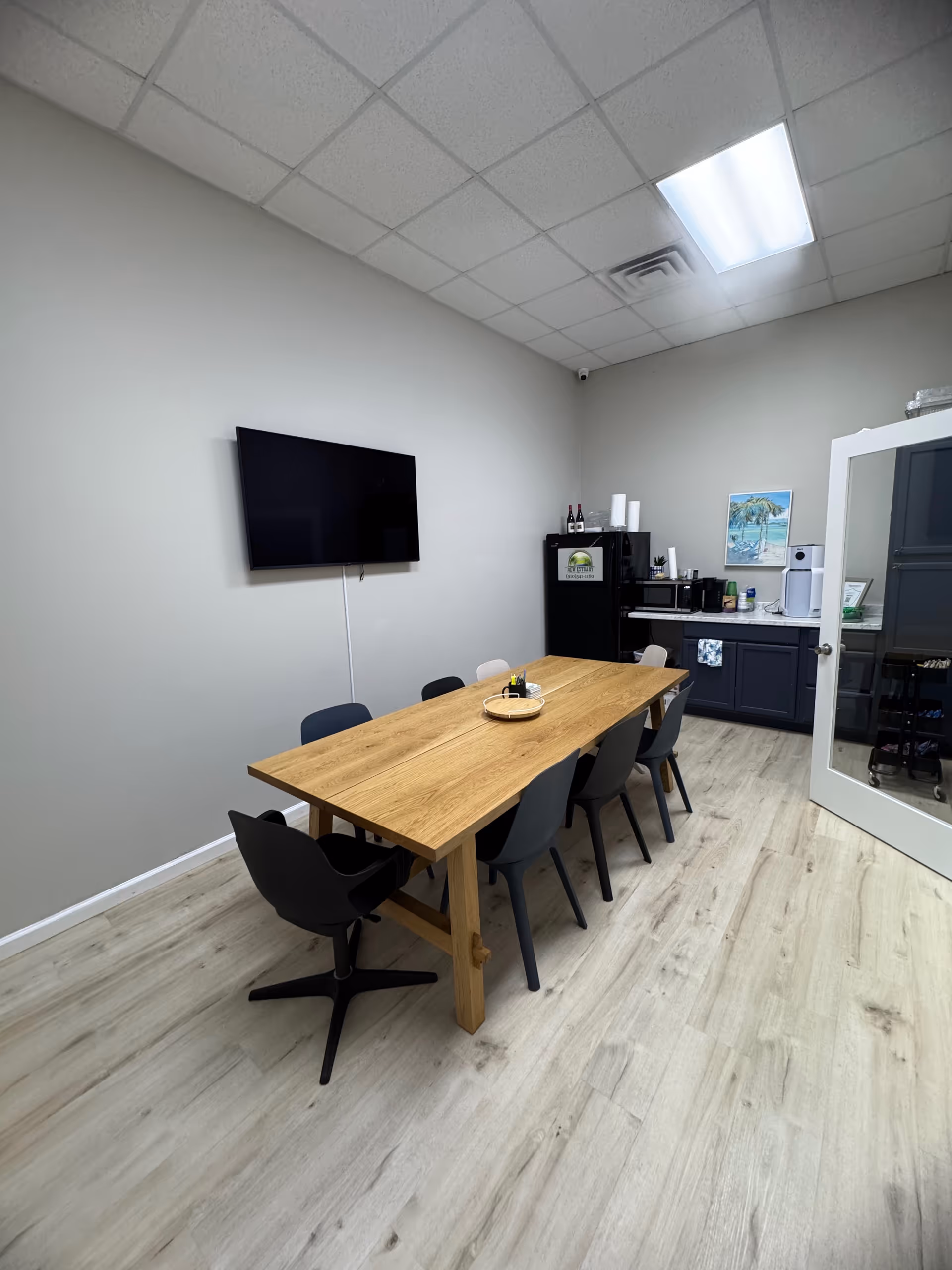 Wooden dining table with chairs in a bright, minimalist communal room.
