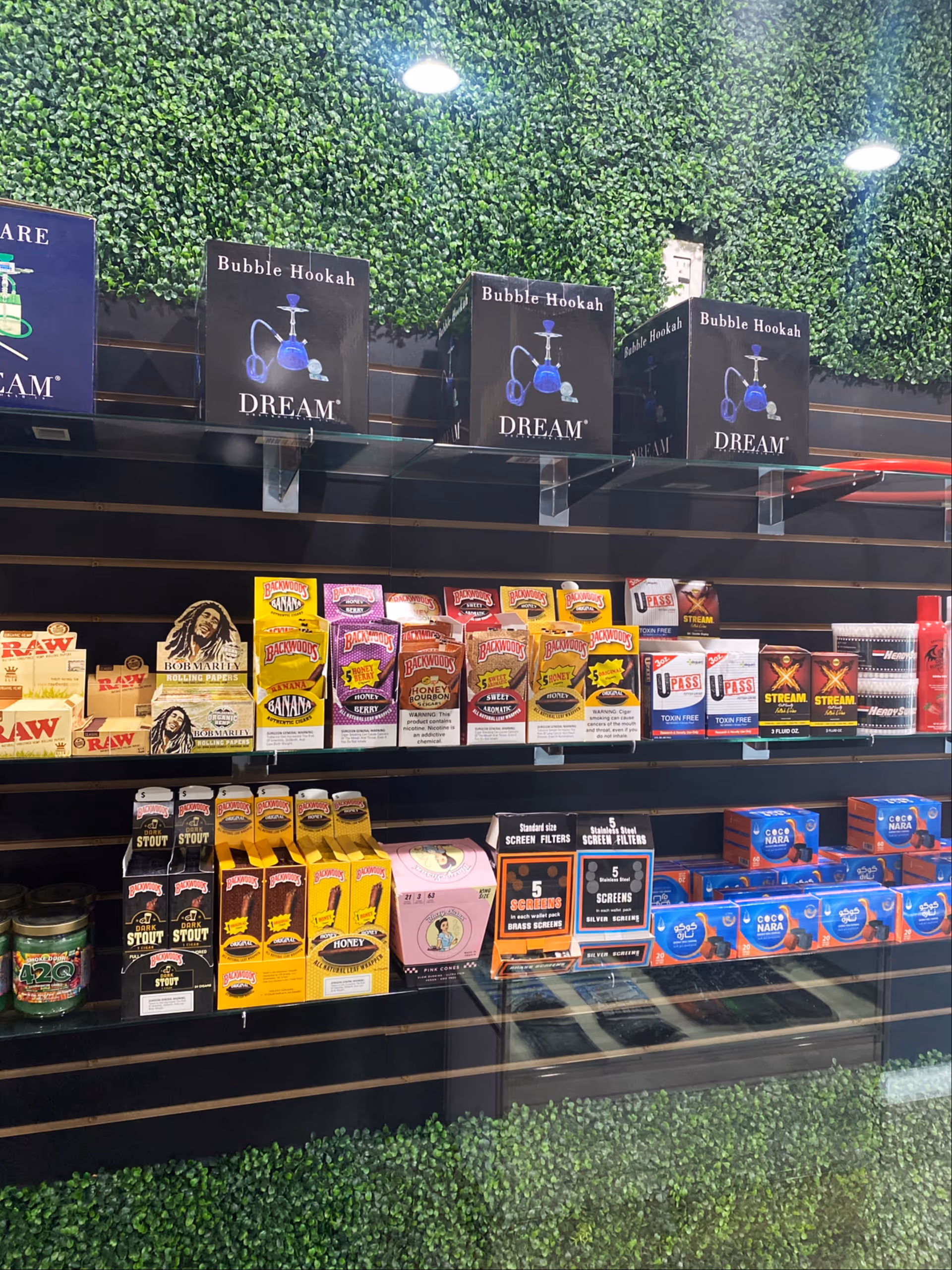 Indoor shop shelves display hookah boxes and assorted smoking products.