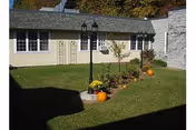 Front exterior of a senior living building with a manicured lawn and pumpkins.