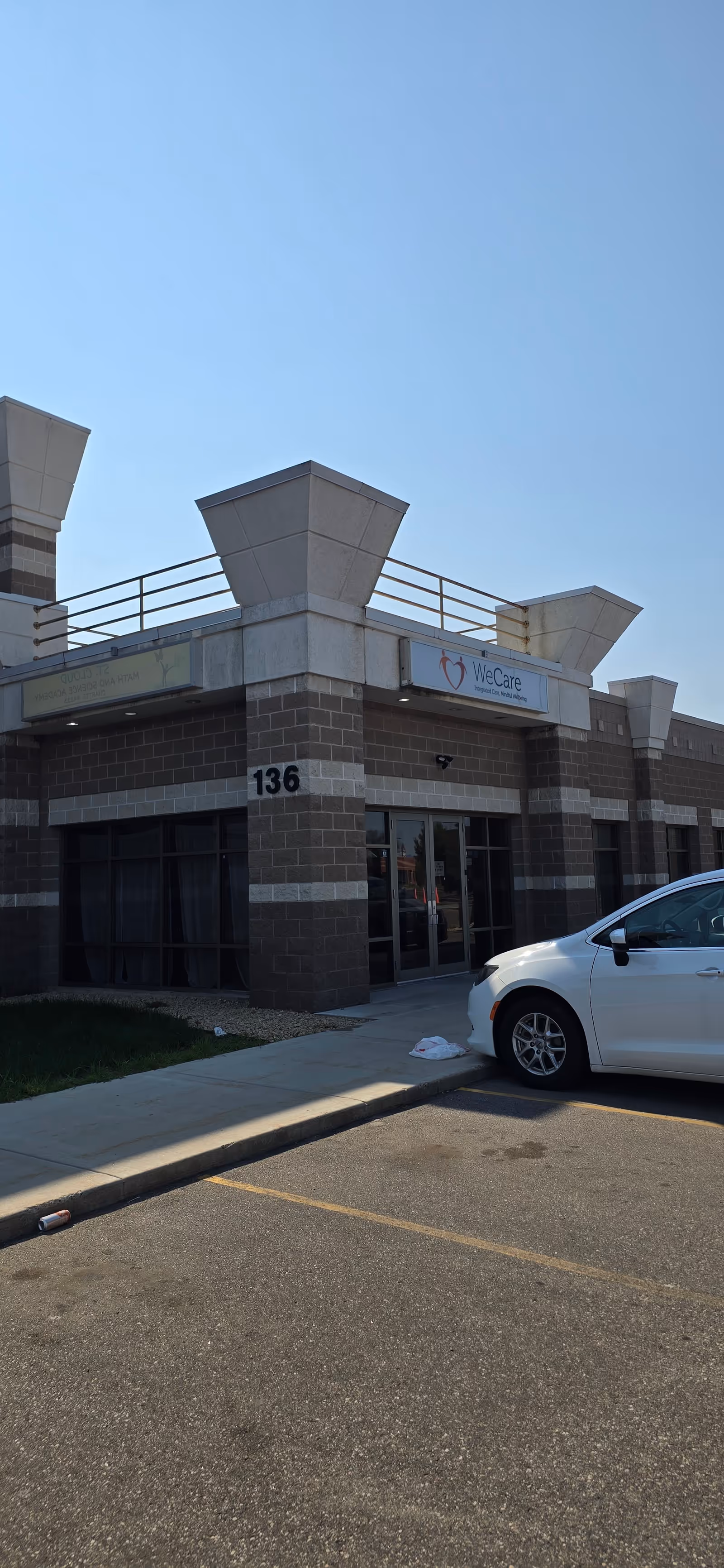 Exterior view of a WeCare senior living building with a white car parked at the entrance.
