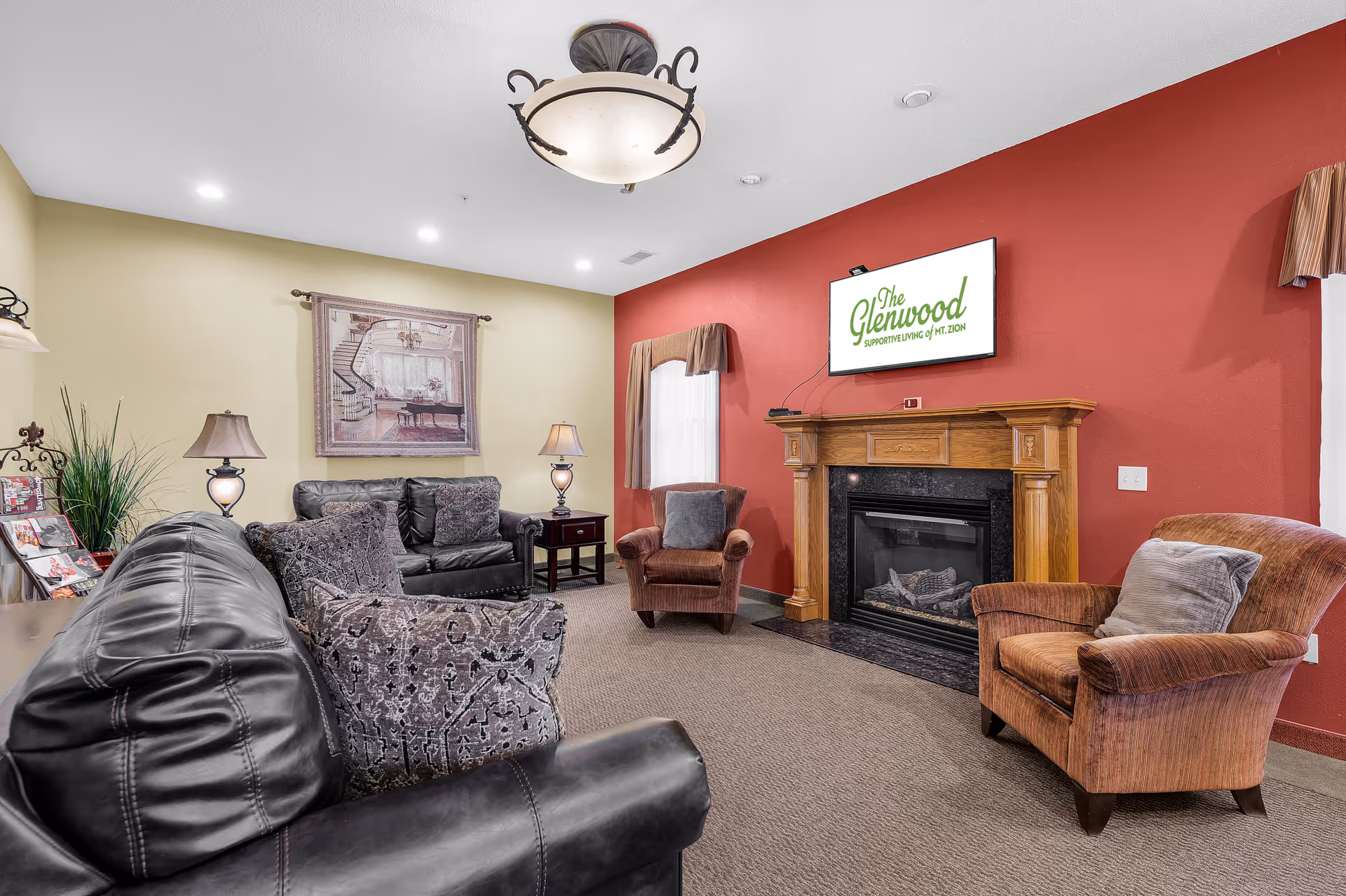 Cozy lounge with leather sofas, fireplace, and mounted TV in a warm common area.