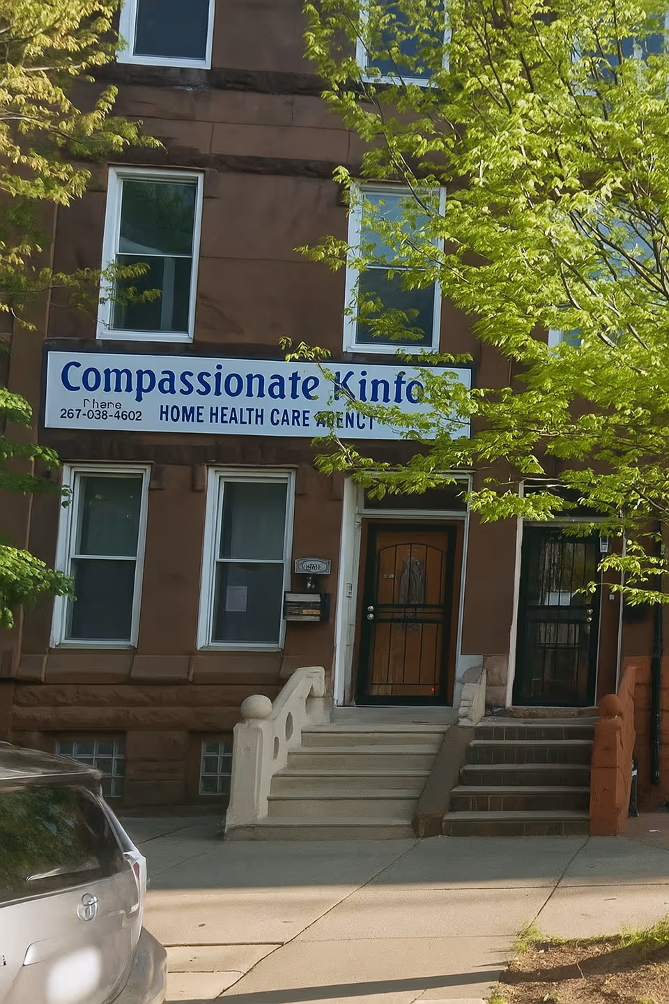 Front view of a brown brick building with a blue Compassionate Kinfolk sign.
