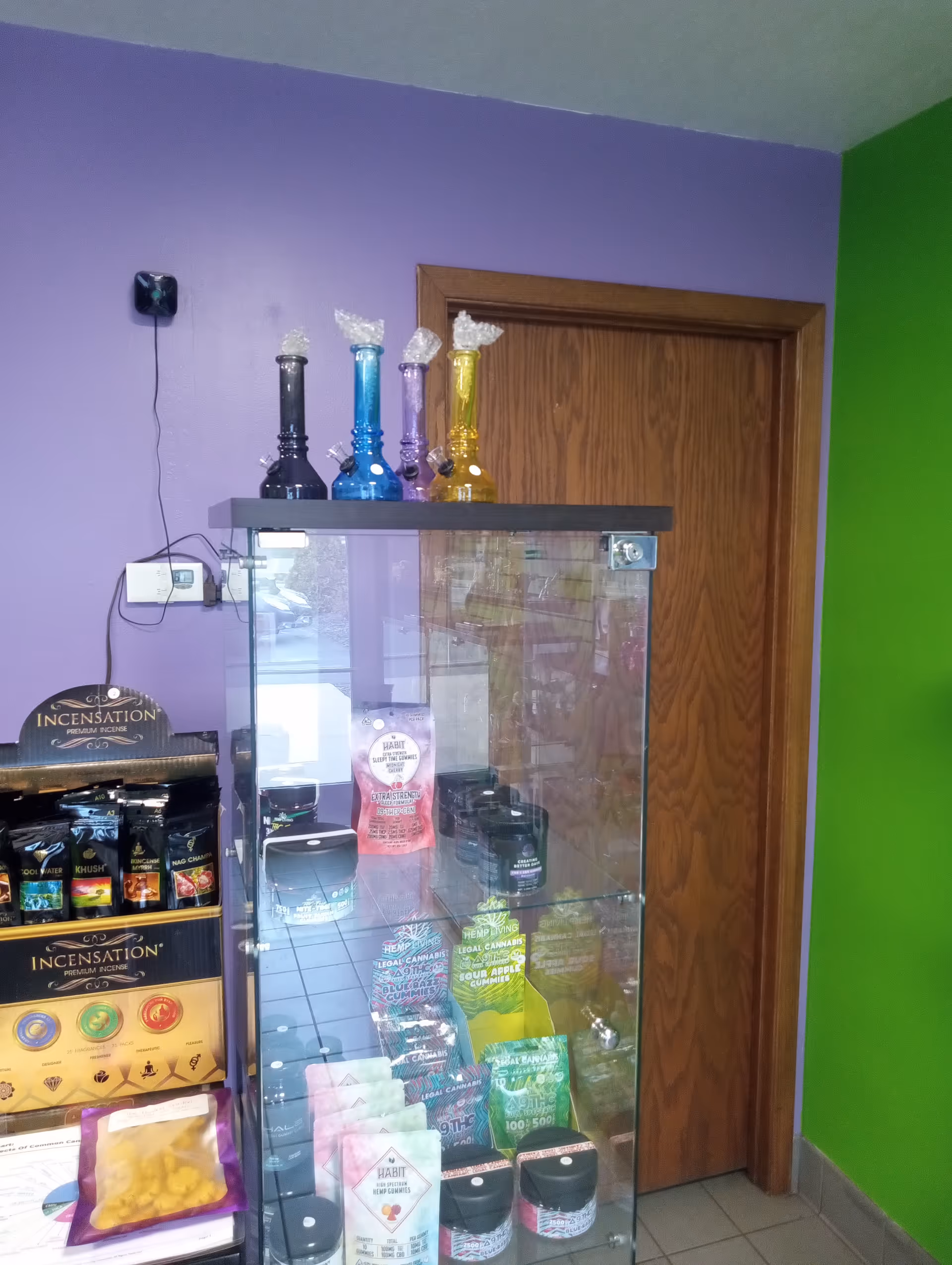 Purple and green interior with a glass display cabinet of colorful glass pipes and incense.