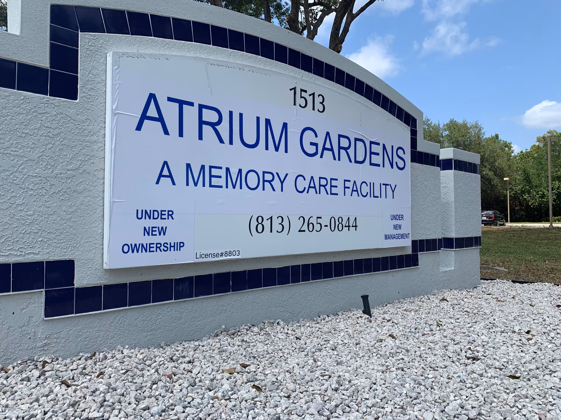 Front view of Atrium Gardens sign on exterior wall with gravel.