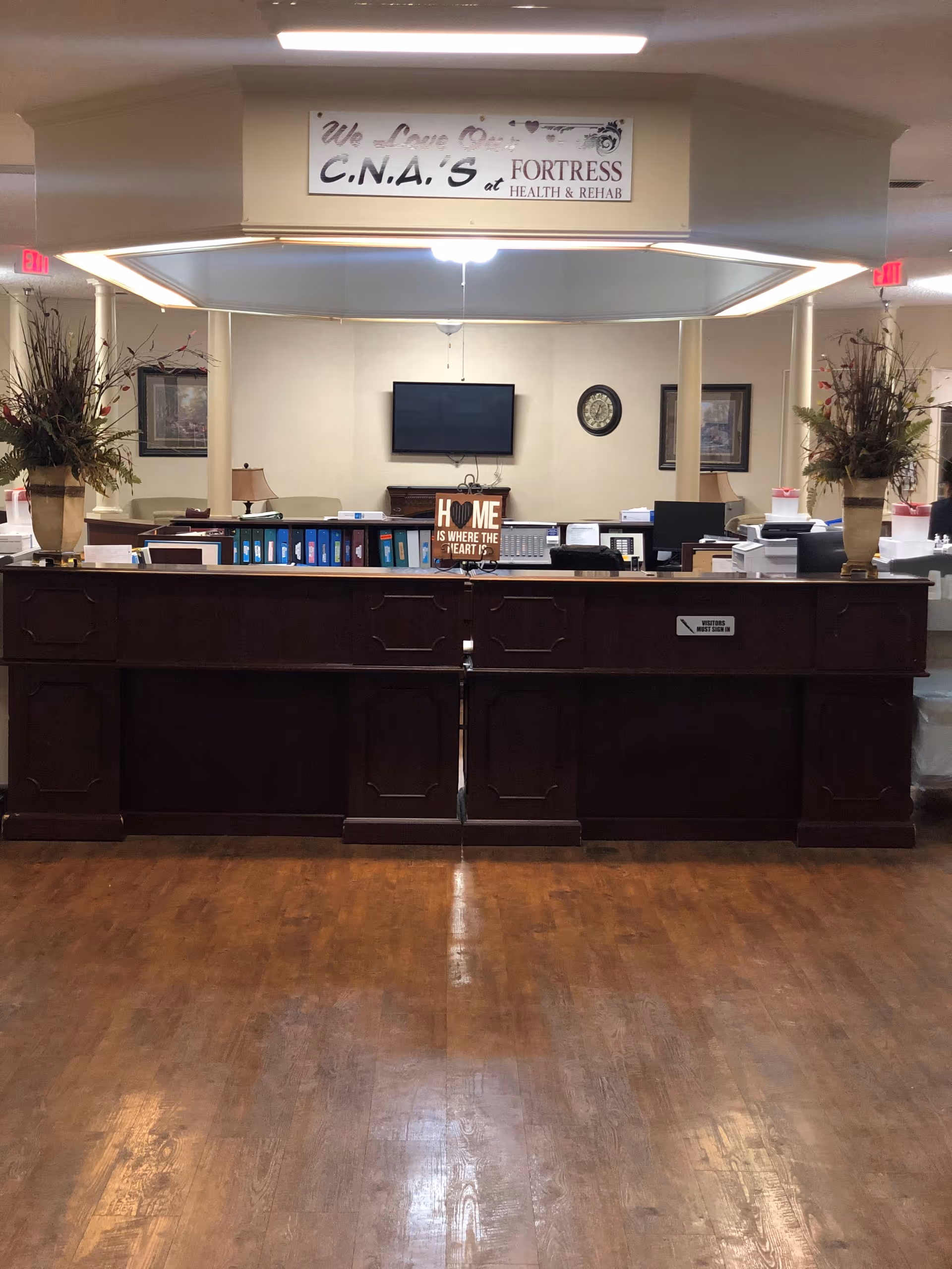 Interior lobby of Fortress Nursing and Rehabilitation with a front desk, TV, and décor.