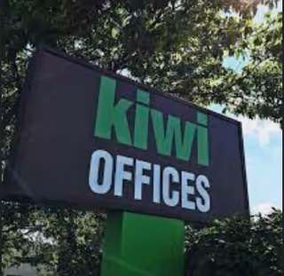 Outdoor building sign reading 'kiwi OFFICES' with trees in background.