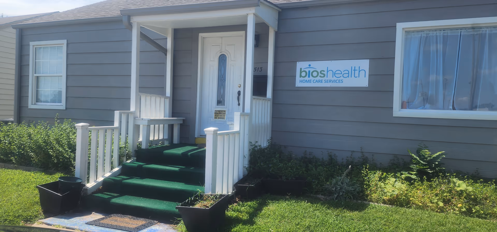 Gray single-story facility exterior with green steps, white railings, and a BiosHealth sign.