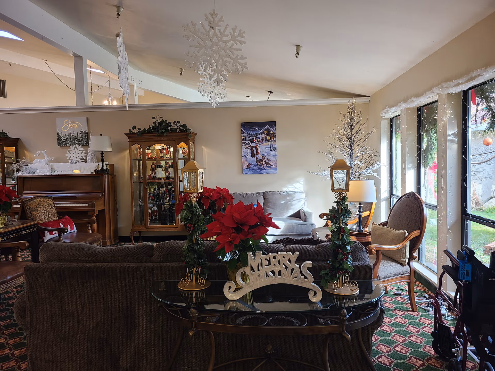 Cozy senior living lounge decorated for Christmas with poinsettias and a piano.